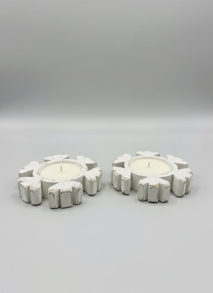 Decorative candle holders shaped like snowflakes on a wooden surface.