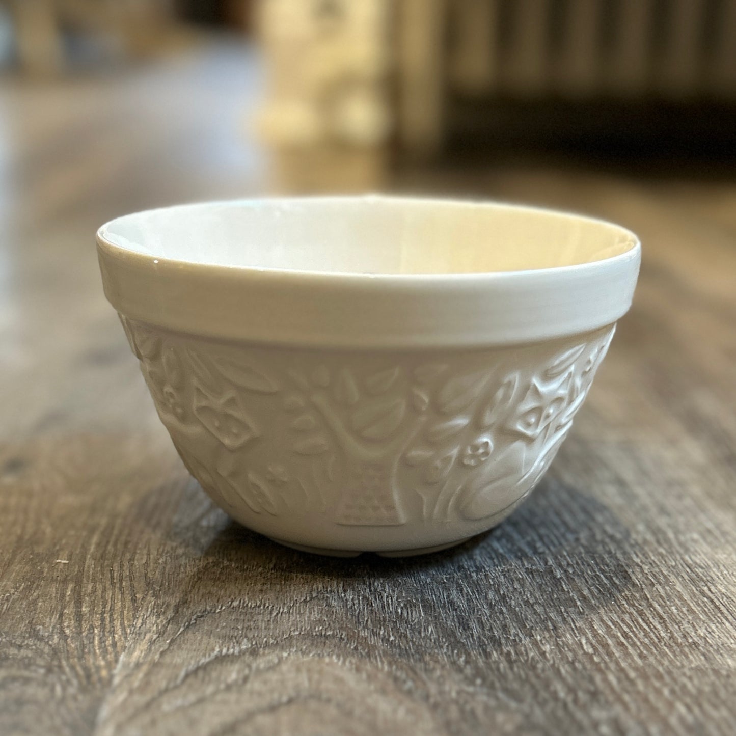 Photo containing a small mixing bowl. Made of white glazed ceramic. Forest scene surrounds the bowl with details of trees, leaves, and foxes.