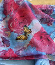 Load image into Gallery viewer, A blue scarf is shown with pink flowers and butterfly pattern. The fabric is light and slightly see through.
