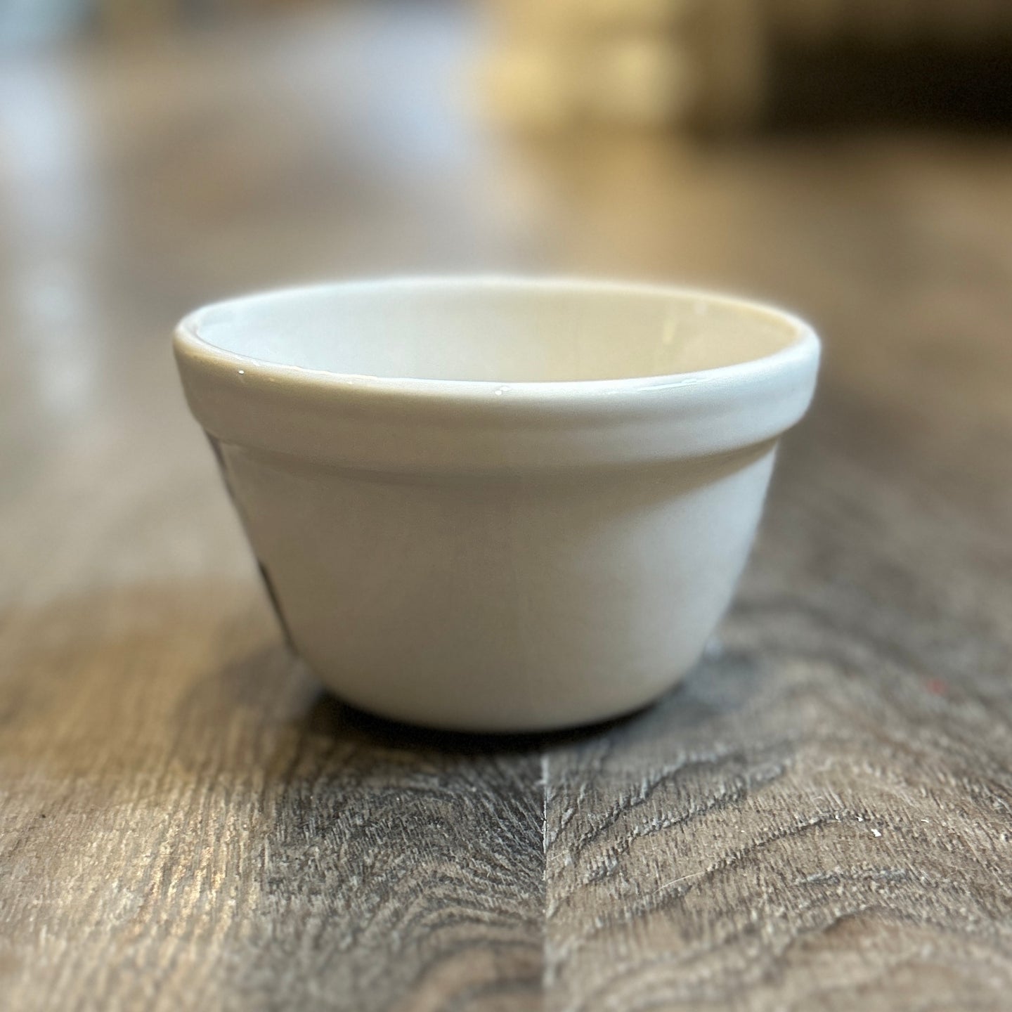 Photo of a small white bowl with a thick rim. Made of white glazed ceramic. 